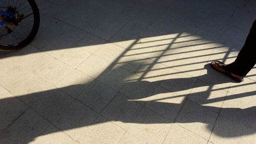 Low section of person shadow on tiled floor