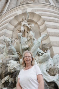 Portrait of smiling woman standing against statues