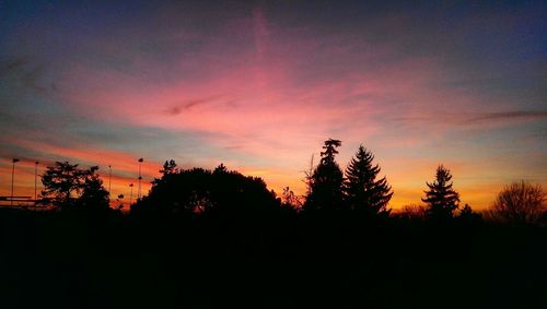 Silhouette trees against dramatic sky during sunset