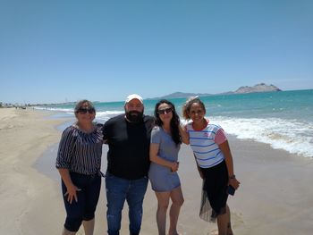 Friends standing on beach against clear sky