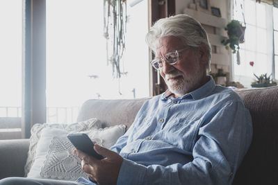 Midsection of man using mobile phone while sitting on sofa at home