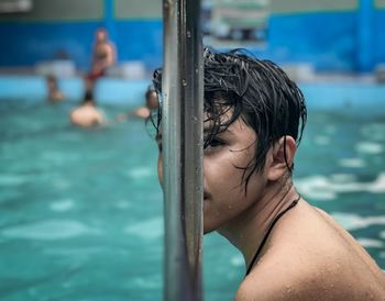 Portrait of shirtless man by swimming pool