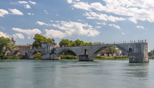Arch bridge over river against cloudy sky