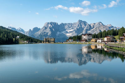 Scenic view of lake by buildings and mountains against sky