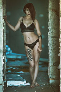 Portrait of young woman standing against wall