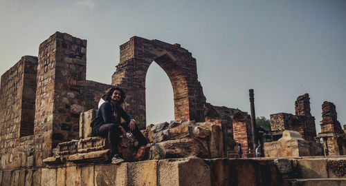 Old ruins against sky with a guy sitting on stone seats