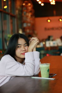 Portrait of young woman sitting at restaurant table
