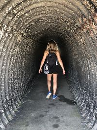 Rear view of woman with backpack walking in tunnel
