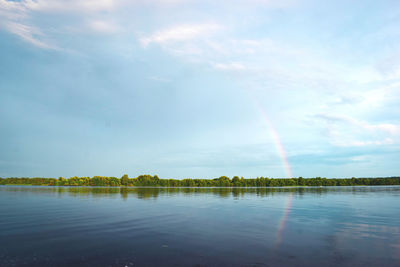 Scenic view of rainbow over lake against sky