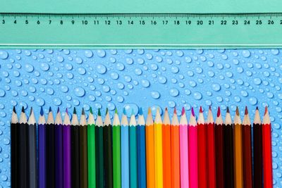 Close-up of colored pencils on wet table by ruler