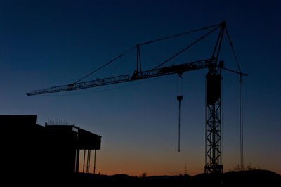 Low angle view of silhouette crane against sky during sunset