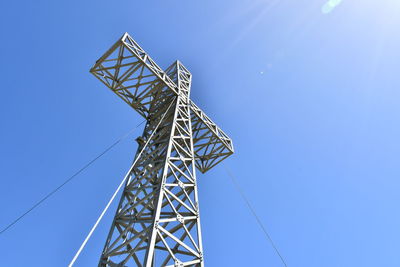 Low angle view of electricity pylon against clear blue sky