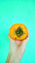 Close-up of person holding apple against blue background