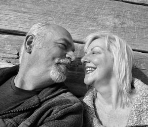 Happy senior couple looking at each other against wooden wall