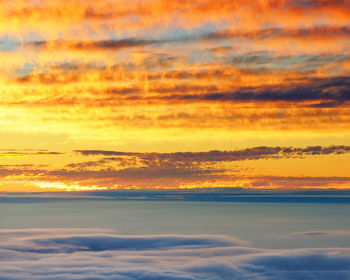 Scenic view of sea against dramatic sky during sunset