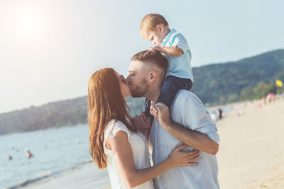 Couple kissing while holding water against sky