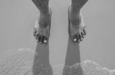 Low section of man standing at beach