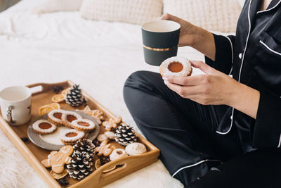 Midsection of woman holding coffee cup while sitting in bed