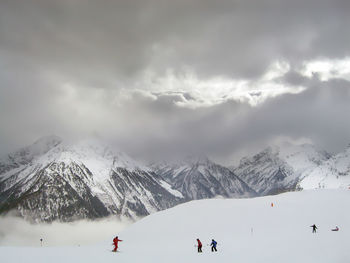 People skiing on snowcapped mountains against sky