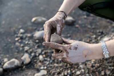 Woman putting mud on hands and face while enjoying outdoors in nature.