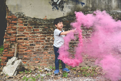 Full length of boy with distress flare standing against brick wall