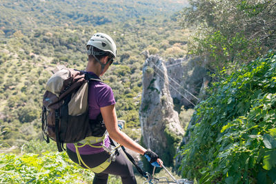 Adventure. woman with helmet, harness and backpack. descending in the mountains by a via ferrata.