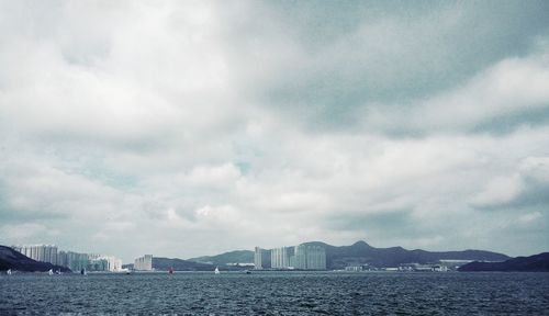 Cityscape by sea against sky