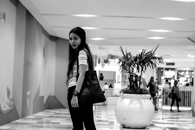 Portrait of young woman standing against wall