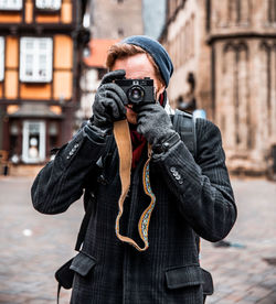 Close up portrait of obscured face male in winter clothing with vintage camera.