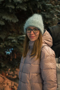 Portrait of young woman standing against trees