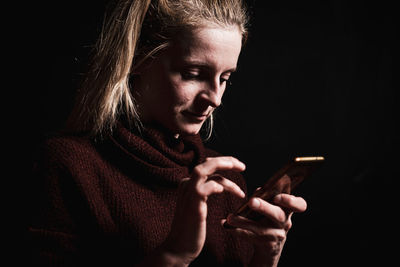 Close-up of woman using smartphone in darkroom