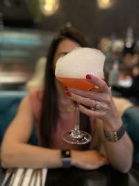 Midsection of woman holding drink in restaurant