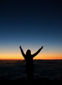 Silhouette woman standing on land against sky during sunset