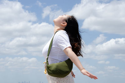 Young woman standing against sky
