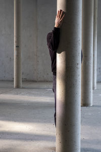 Midsection of woman standing on pole against wall