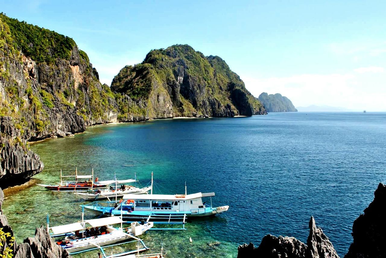 sea, water, nautical vessel, tranquil scene, horizon over water, scenics, tranquility, beauty in nature, boat, mountain, transportation, blue, nature, sky, mode of transport, idyllic, rock formation, rock - object, day, coastline