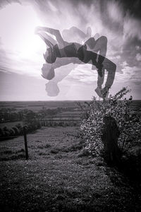 Man jumping on field against sky