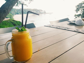 A glass of mango juice with mint leaves is on the table