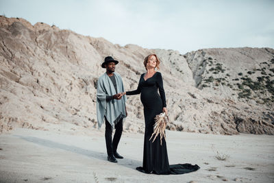 Full length of couple standing on sand in desert