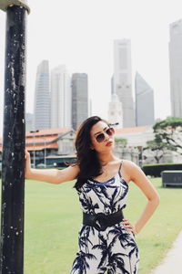 Portrait of young woman wearing sunglasses while standing on footpath