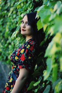 Portrait of young woman standing against plants