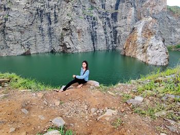 Young man sitting on rock by lake.