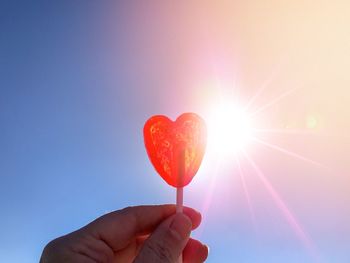 Close-up of hand holding heart shape against sky