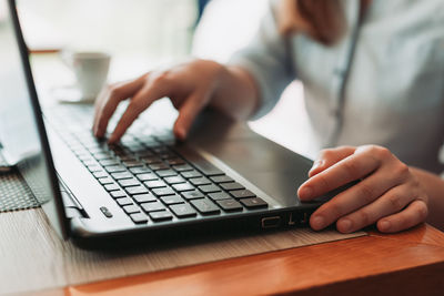 Hands typing on laptop keyboard, freelancer remote work