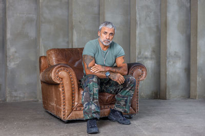 Portrait of senior man sitting against wall