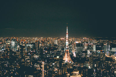 Illuminated tokyo tower amidst cityscape at night