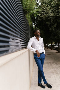 Portrait of man looking away while standing against trees