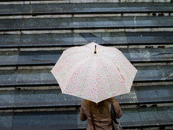 High angle view of woman carrying umbrella on steps