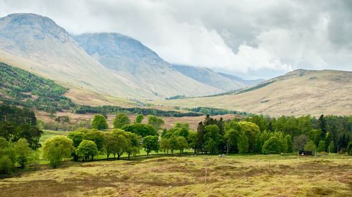 Scenic view of green landscape and mountains against sky