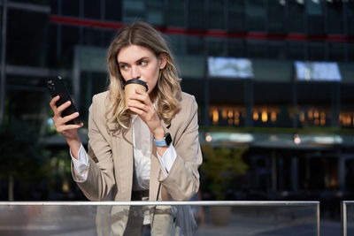 Young woman drinking water in city